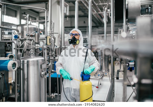 Exterminator in industrial plant spraying\
pesticide with sprayer. Disinfection of the factory due to the\
coronavirus\
epidemic.