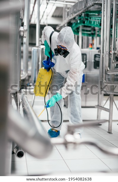 Exterminator in industrial plant spraying\
pesticide with sprayer. Disinfection of the factory due to the\
coronavirus\
epidemic.