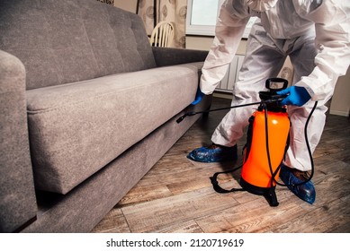 An exterminator in work clothes sprays pesticides with a spray gun. Fight against insects in apartments and houses. Disinsection of the premises