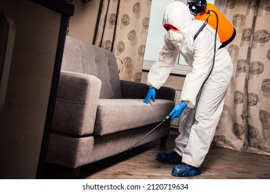 An Exterminator In Work Clothes Sprays Pesticides With A Spray Gun. Fight Against Insects In Apartments And Houses. Disinsection Of The Premises