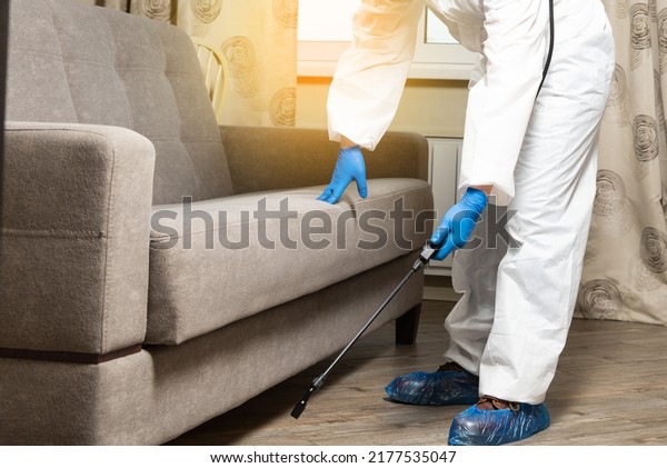 An exterminator in work clothes sprays\
pesticides from a spray bottle. Fight against insects in apartments\
and houses. Disinsection of\
premises.