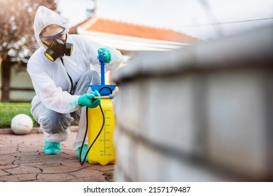 Exterminator In Work Wear Outdoors Spraying Pesticide With Sprayer