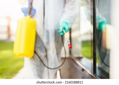 Exterminator In Work Wear Outdoors Spraying Pesticide With Sprayer