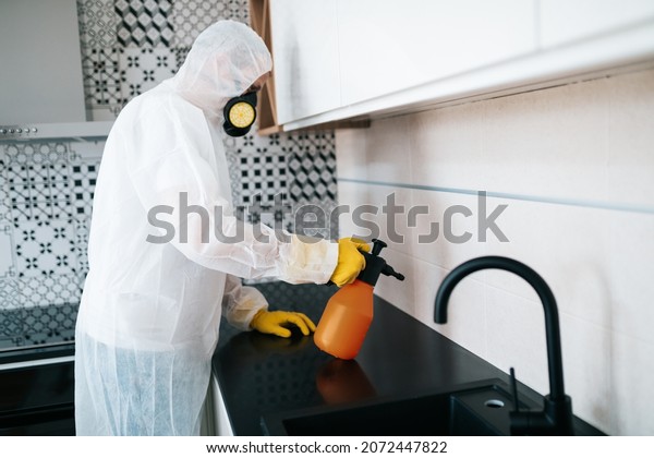 Exterminator in work wear spraying pesticide with\
sprayer. Selective\
focus.