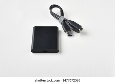 External compact SSD-drive with USB cable for writing, reading and storing data on a white background. - Shutterstock ID 1477672028