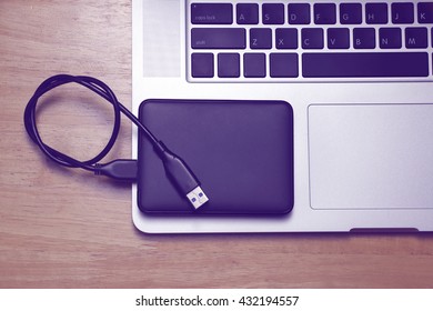 External hard disk and laptop computer on wood background.