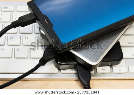 External harddisk 3 drive on laptop table wood.
External hard drive on keyboard desk wooden. 
top view.