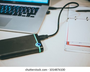 external hdd (ssd) connected to the laptop on the white surface