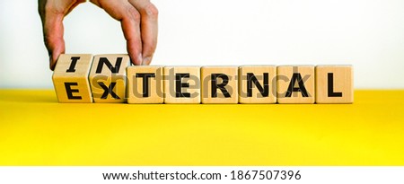 External or internal symbol. Male hand flips wooden cubes and changes the word 'external' to 'internal'. Beautiful yellow table, white background, copy space. Business concept.