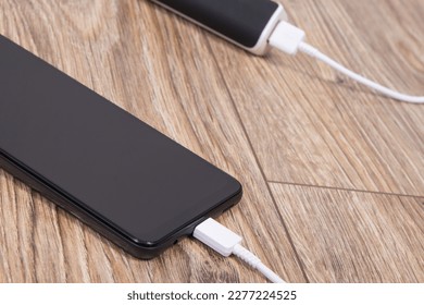 External powerbank using to charge empty battery of black smartphone or mobile phone