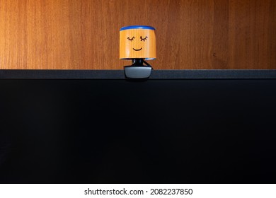 External Round Black Web Camera With A Smiling Cap On A Black Monitor. Smiling Cover For A Webcam. Protection Against Spying.