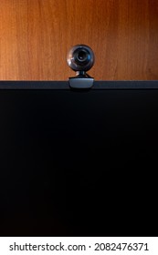External Round Black Web Camera On A Black Monitor. Webcam On A Wooden Background.