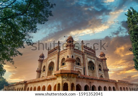 External side 45 degree view of Safdarjung tomb with blue sky and trees in the foreground. This historical monument is a popular tourist place