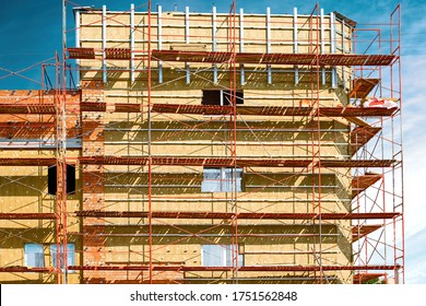 External wall thermal insulation with rock wool, scaffolding arround the house, installation of thermal insulation on building facade, building a new house under construction. Energy efficiency
