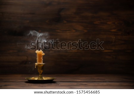 extinct old candle with vintage brass candlestick on wooden background in minimalist room interior with copy space