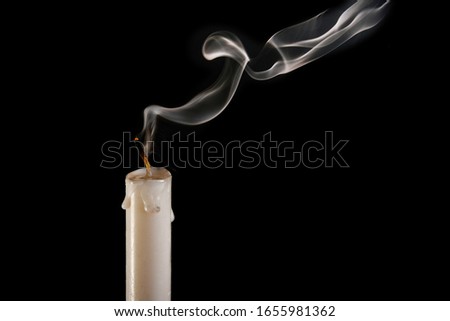 An extinguished candle on a black background, smoke goes from the wick to the top. The concept of completeness and completeness.