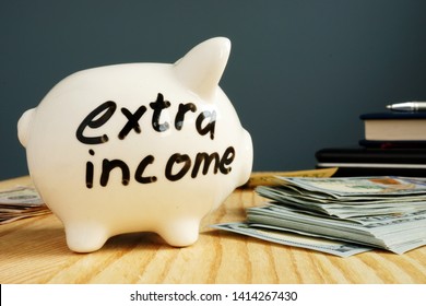 Extra income handwritten on a piggy bank and cash. - Shutterstock ID 1414267430