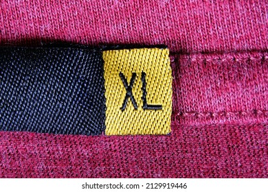 Extra large size or size XL shown on a shirt label. Closeup macro top view. Tag with the letters XL sewn on the inside seam of a garment indicating the dimension or measurement of the clothing.