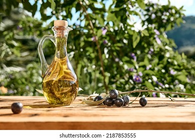Extra virgin olive oil and olive branch in the bottle on wooden table in the olive grove. Healthy mediterranean food.