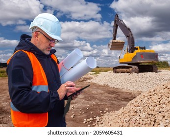 Extraction of stone. Male worker next to stone quarry. Engineer at construction site. Stone quarry worker with papers. He's calling someone on phone, excavator with bucket in background.
