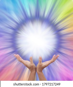 Extraordinary Multicoloured Energy Field Formation - female cupped hands reaching up to a bright white orb surrounded by rainbow colours radiating outwards with copy space 
