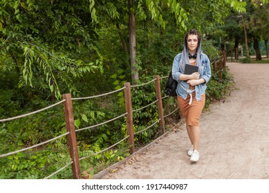 Extraordinary woman student millennial with african pigtails walking in the park