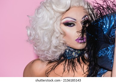 Extravagant Drag Queen Looking At Camera Near Feather Boa Isolated On Pink