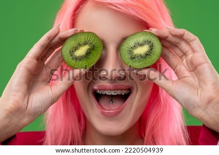 Extravagant female with kiwifruit posing for the camera indoors