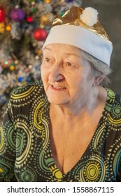 Extravagant Old Woman With Gray Hair And Wrinkles In Glasses. Senior Citizen In Santa Claus Hat. Concept Of Domineering And Funny Elderly Mother In Law. Christmas Eve