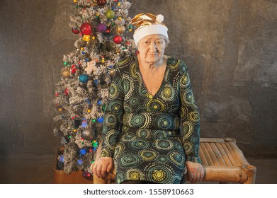 Extravagant Old Woman With Gray Hair And Wrinkles In Glasses. Senior Citizen In Santa Claus Hat. Concept Of Domineering And Funny Elderly Mother In Law. Christmas Eve