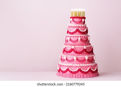 Extravagant pink tiered birthday cake decorated with vintage buttercream piped frills and gold birthday candles - Shutterstock ID 2160779243