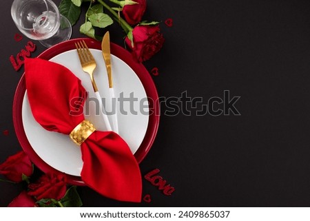 Extravagant Valentine's Day dining affair. Top view flat lay of plates, cutlery, hearts, red roses, wineglass, red napkin on black background with promo space