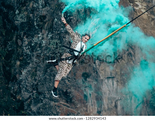 Extream sportgirl jumps with rope and blue smoke.\
Bungee or rope jumping