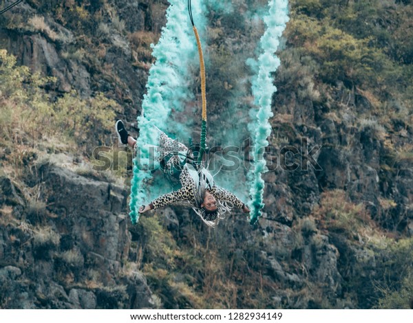 Extream sportgirl jumps with rope and blue smoke.\
Bungee or rope jumping