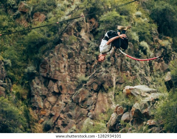 An extream sportman jumps in a rope\
on a big hight. Danger sport, bungee/rop\
jumping.