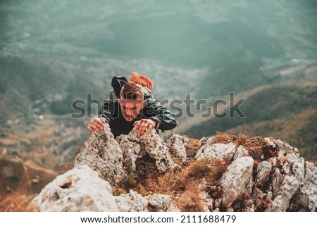 Extreme adventure adrenaline sport. Courage man climbing up on the top mountain peak.	