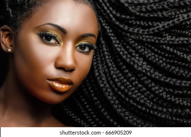 Extreme close up beauty portrait of young african woman showing long braided hair next to face.
