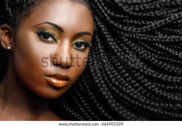 Extreme close up beauty\
portrait of young african woman showing long braided hair next to\
face.