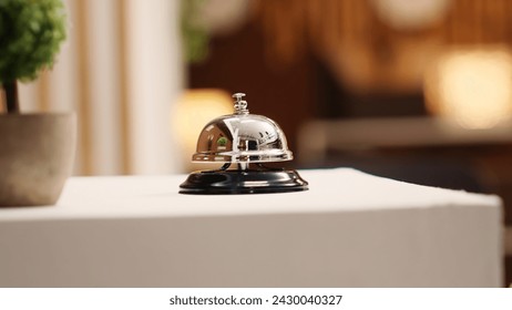 Extreme close up of concierge bell next to mini plant on cozy hotel lounge check in desk. Elegant service bell on modern stylish hospitality industry resort reception counter - Powered by Shutterstock