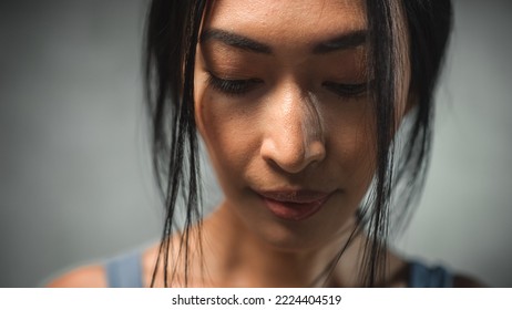 Extreme Close Up of the Face of a Asian Female Looking Down. Strong Young Woman Thinking and Contemplating, Fighting Against Mental Illness. She is Making Decisions to Improve her Wellness