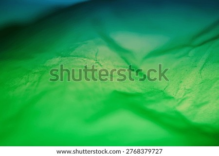 Extreme close up of green plastic texture background. The plastic surface is wrinkly and tattered making abstract pattern. Selective focus, shallow depth of field.