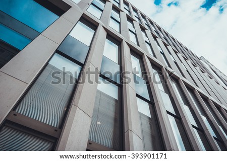Extreme Close Up and Low Angle View of Modern Commerical Office Building with Vertical Windows, Architectural Exterior Against Blue Sky with White Clouds