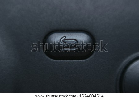Extreme close up macro shot of reverse button with arrow on black matte plastic game pad
