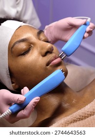 Extreme close up of microcurrent electrodes on African American woman's face. Professional lifting procedure for skin tightening and rejuvenation.
