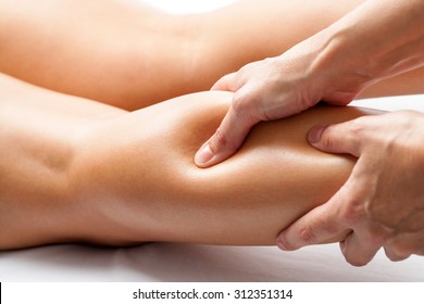 Extreme Close Up Of Osteopath Applying Pressure With Thumb On Female Calf Muscle.