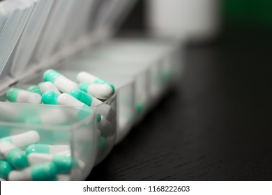 Extreme Close Up Of Seven Day Pill Box With Pills. Blu Pill-box With Tuesday Pills Visible. Open Pill Box On Black Background