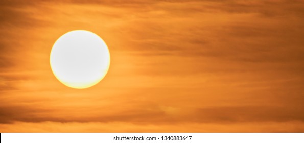 Extreme close up of the sun setting with dramatic red clouds at sunset. Panoramic image. High Definition - Shot with pro zoom lens
