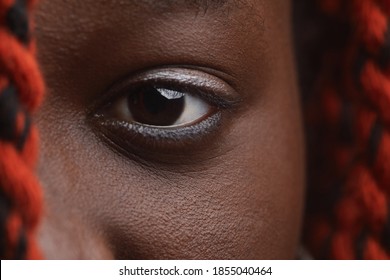 Extreme close up of young African-American woman with braided hair focus on intense brown eye looking at camera, copy space - Powered by Shutterstock