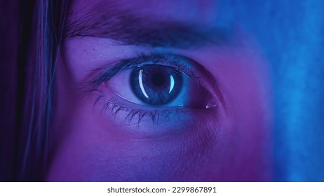 Extreme close-up Beautiful girl opens one eye, neon pink blue light. Attractive feminine look. Party nightclub, fashion show. Macro slow motion. The woman plays video games. Urban eyesight concept. - Powered by Shutterstock