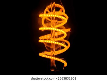 An extreme closeup of a glowing spiral light bulb, emitting a warm light, isolated against a dark background.  - Powered by Shutterstock